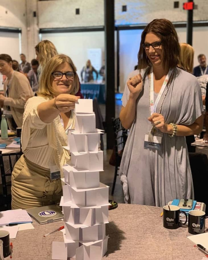 Two women attendees of the Lakeland Fundraising Lab building a paper tower