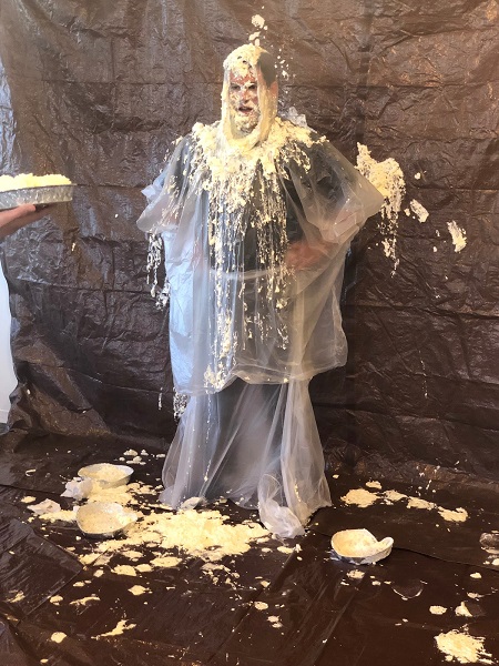 An employee getting a pie in the face after raising the most money in a company-wide peer-to-peer sub-event