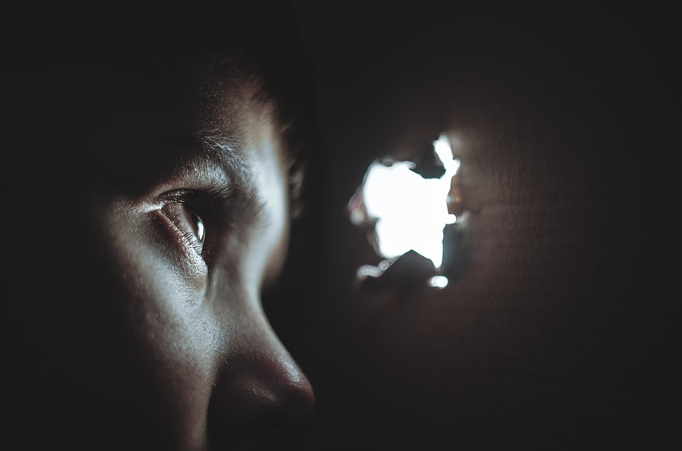 Person looking through a hole in a box, seeking a clue during a scavenger hunt. Done well, scavenger hunt events won't require many volunteers.