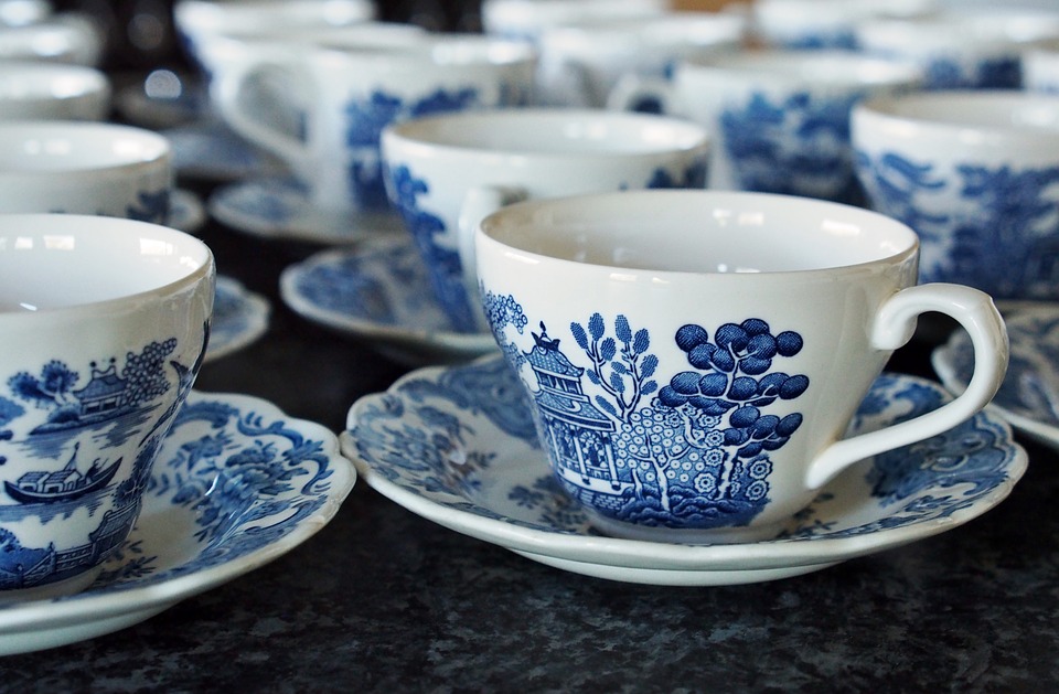 Rows of teacups lined up for a tea party. Volunteers would pass out the tea cups, pour tea, collect cups for cleaning, and brew tea at your event.