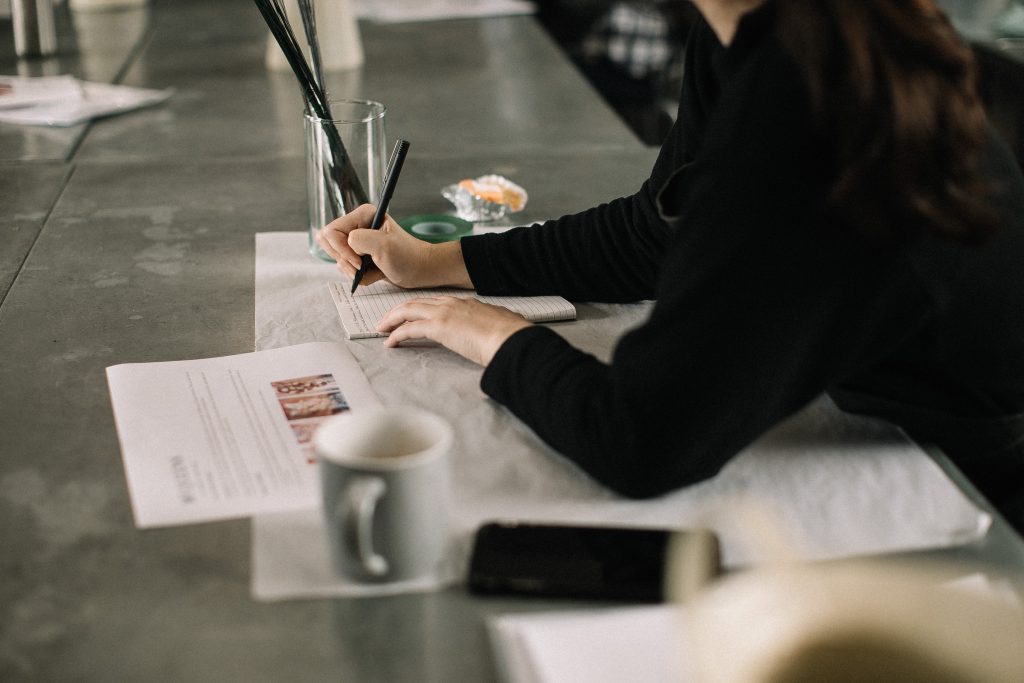 Woman taking notes based on donor research info in front of her.