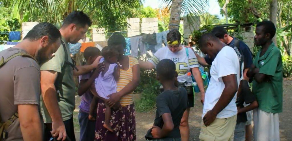 Missionaries praying with Haitian citizens after a successful day of mission work.