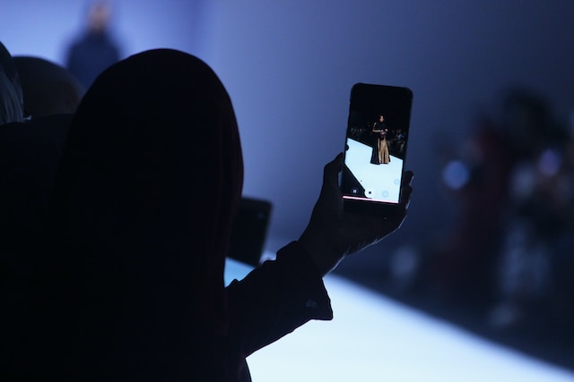 person holding a phone that is recording a fashion show for college fundraising ideas