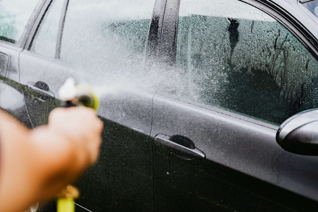 Someone hoses off a car that is being washed.