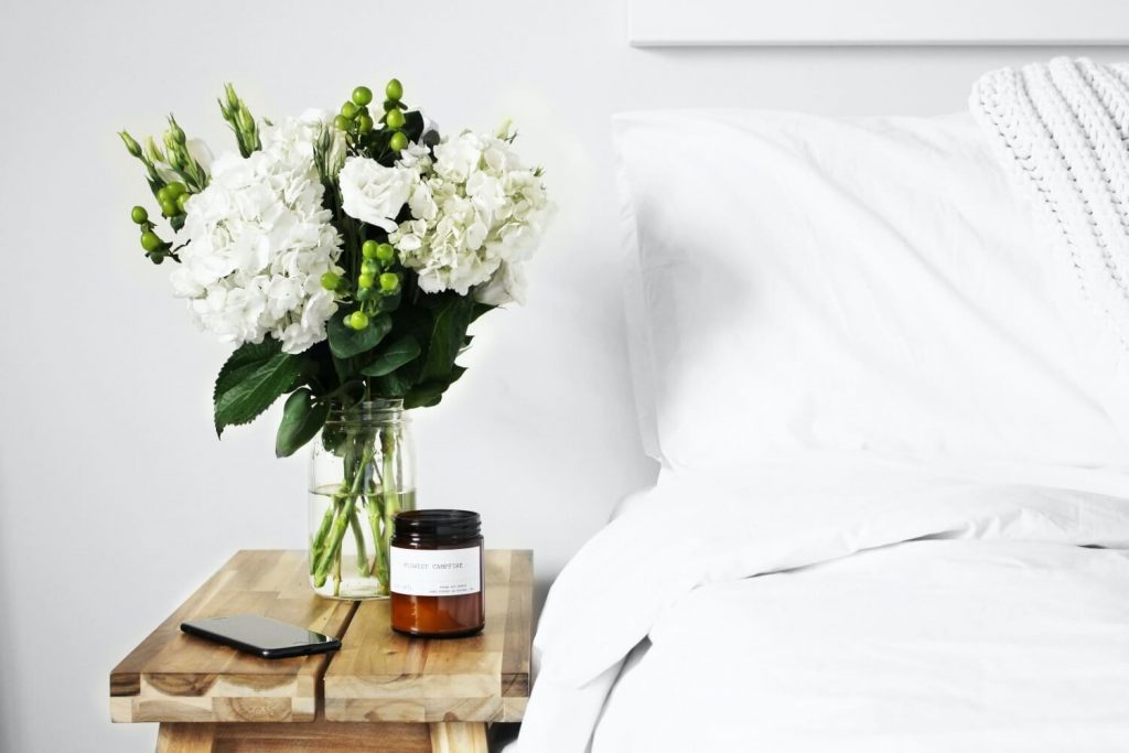 vase of flowers and candle on a nightstand for home good raffle prize ideas