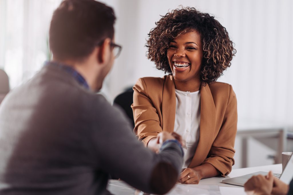 Happy businesswoman shaking hands with colleague after successful meeting