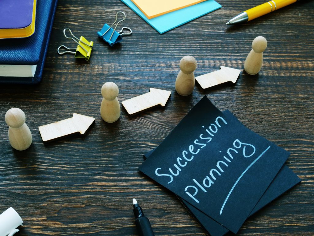 Succession planning sign and figurines with arrows.