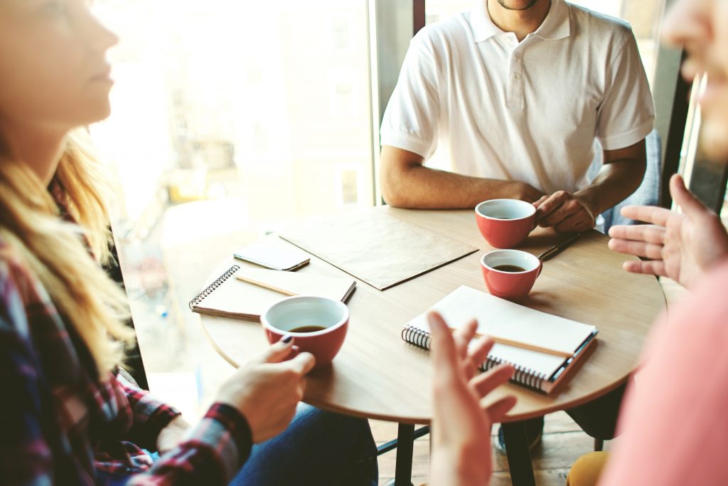 Three people meeting over coffee in cafe to plan and discuss project