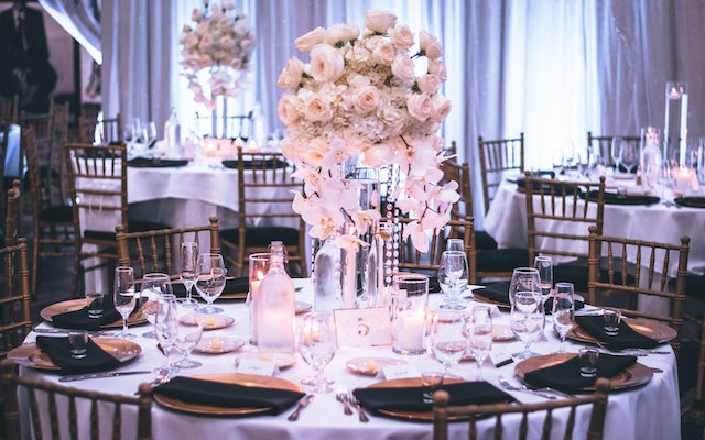 Gala tables set with centerpieces, place settings, wine glasses, and a water bottle.