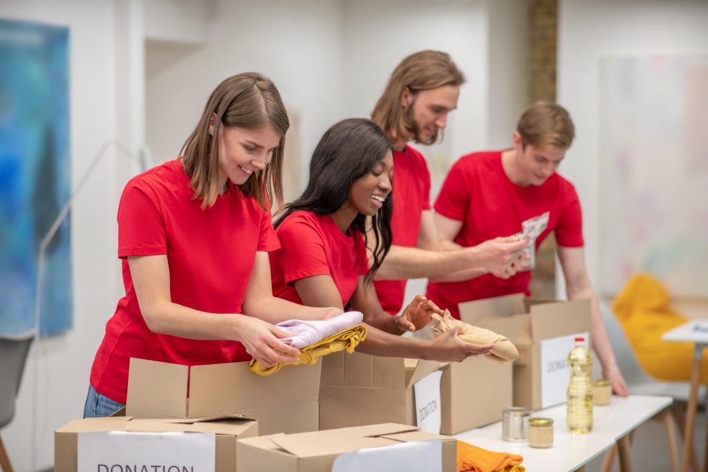 Volunteers. Young people in red packing the cardboards with humanitarian help