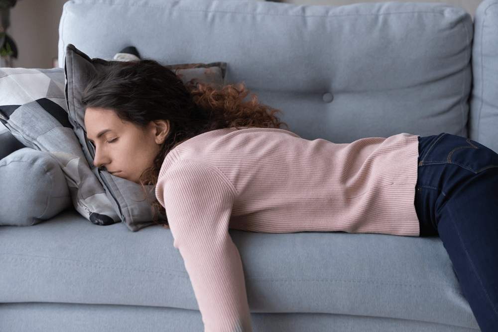 Tired woman lying on a couch face down with eyes closed