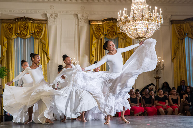 Women dancing in ballroom as other dancers watch from background