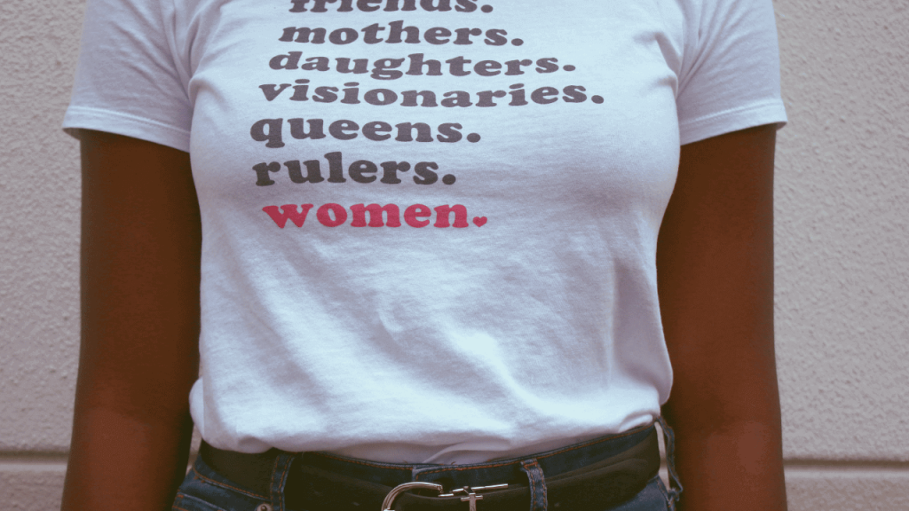 close up of a woman's shirt that says "friends, mothers, daughters, visionaries, queens, rulers, women" for women's history month