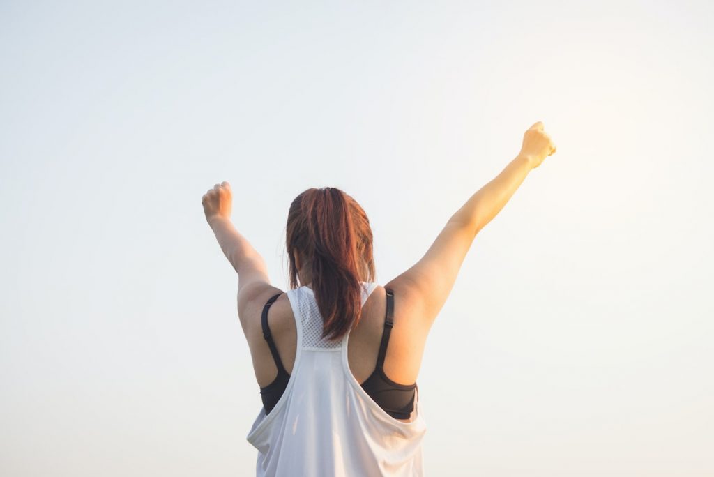 crowdfunding for nonprofits - motivate your supporters; woman in athletic wear raising hands in the air