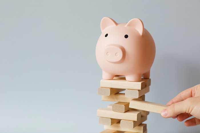 challenges for nonprofits - economic uncertainty; piggy bank on top of a wobbly Jenga game