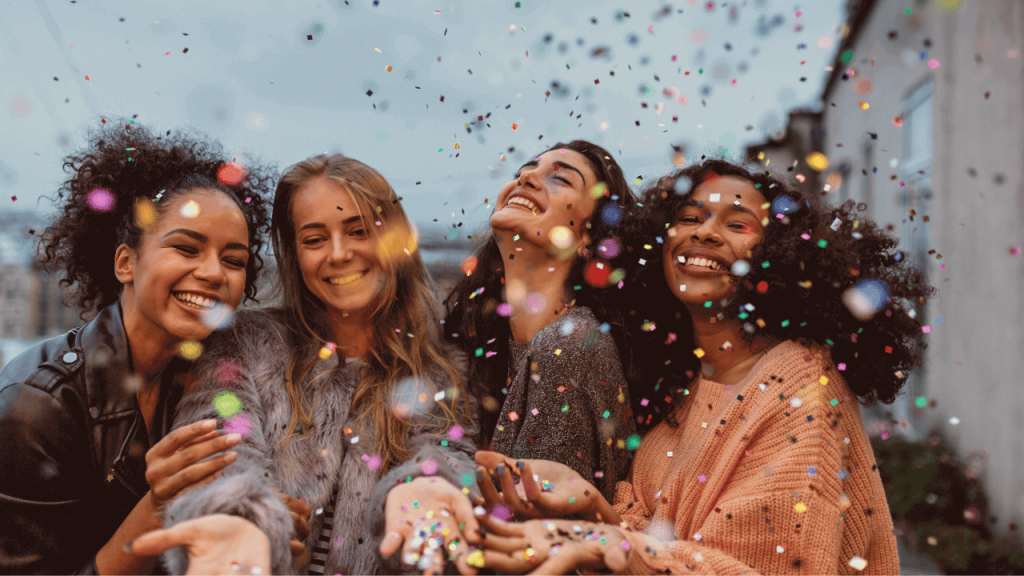 Four women celebrating women's history month with confetti