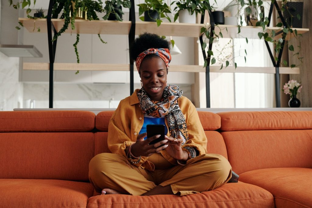 woman sitting on a couch, engaging with her smartphone on social media