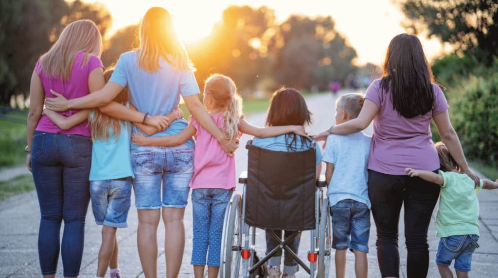 Group of 8 people with arms around one another celebrating Disability Pride Month