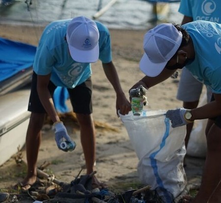 two volunteers picking up trash on the beach for volunteer retention