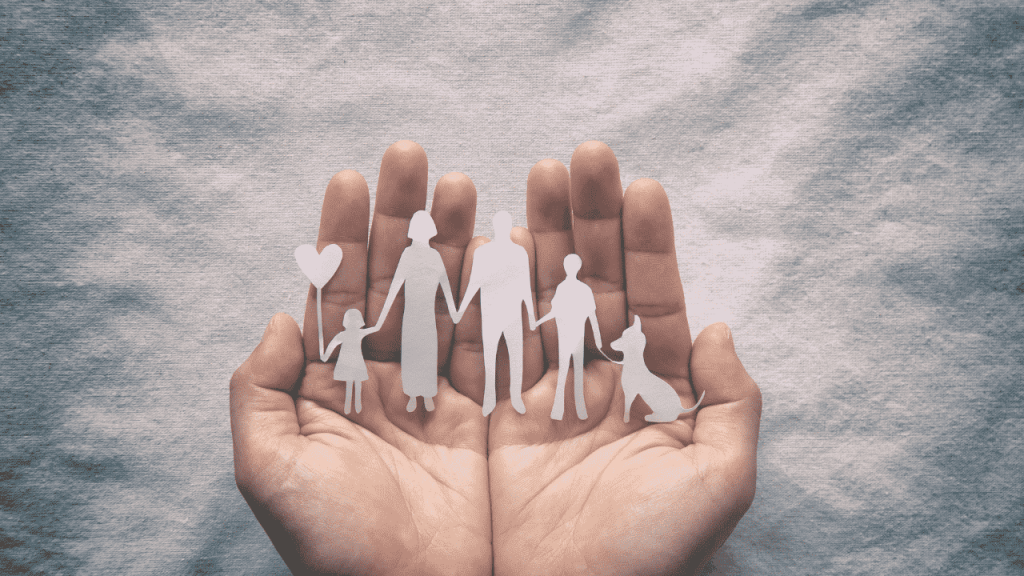 hands holding a paper cutout of a family