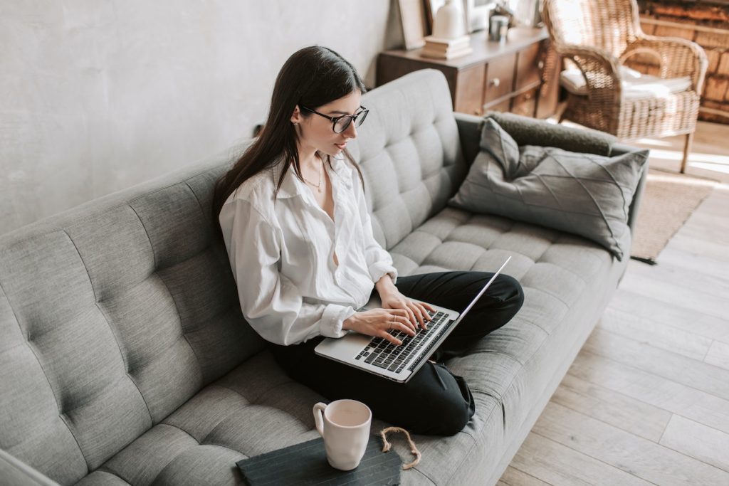 woman using a laptop on a coach with coffee for fundraising automation