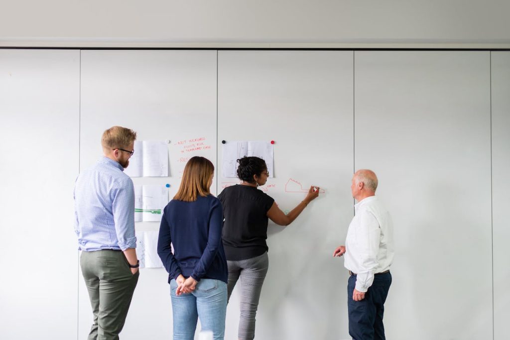 four people performing prospect research at a whiteboard