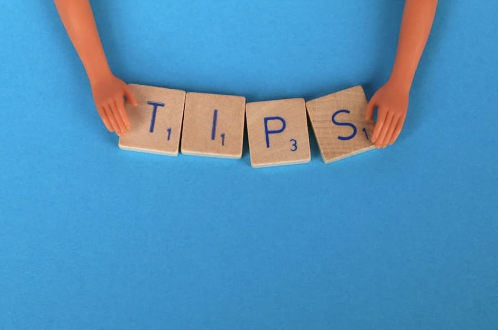 doll hands holding scrabble pieces that spell out TIPS