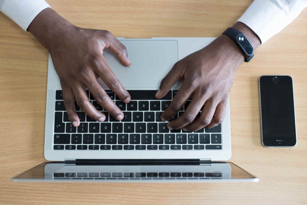 close up aerial view of two hands typing a fundraising letter on a computer keyboard