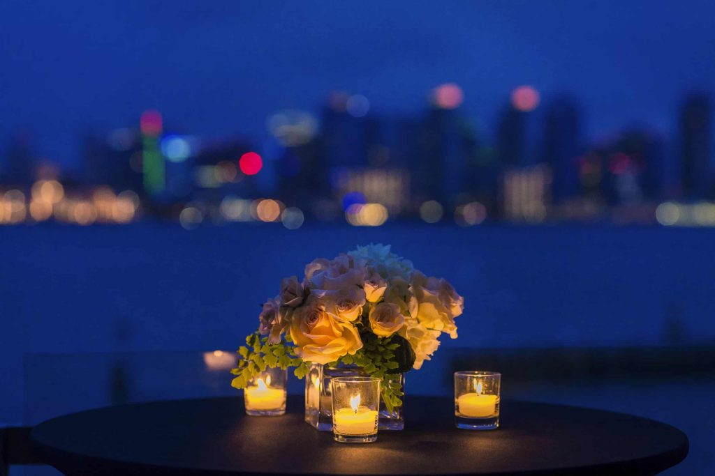 candles and flowers on a table overlooking the water at night for a donor appreciation gala